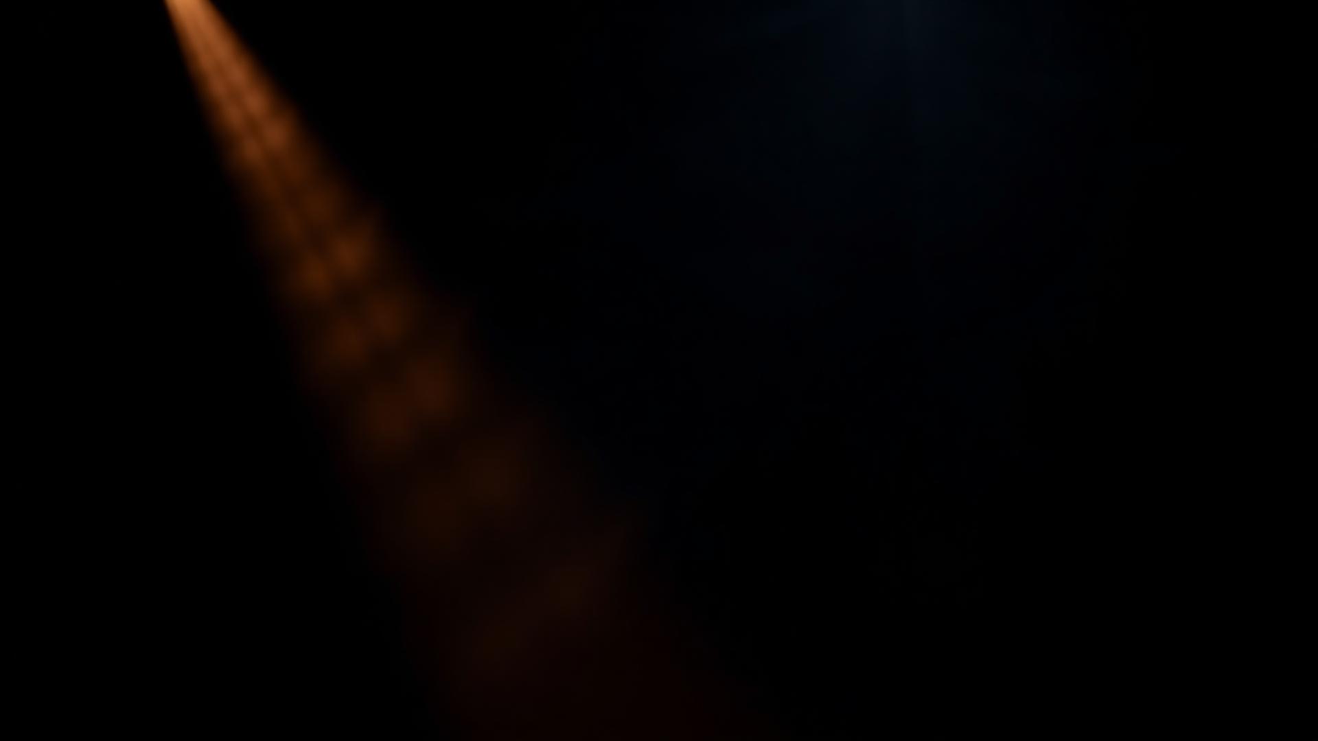 Dark studio lit by a single beam of amber light